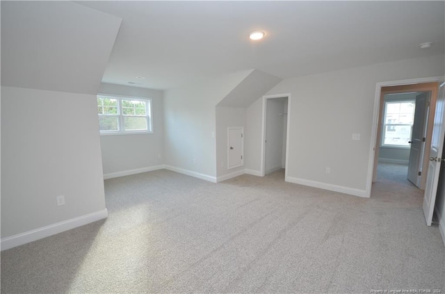 bonus room featuring light carpet, a healthy amount of sunlight, and vaulted ceiling