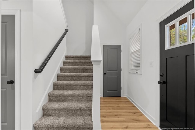 staircase featuring wood-type flooring and vaulted ceiling