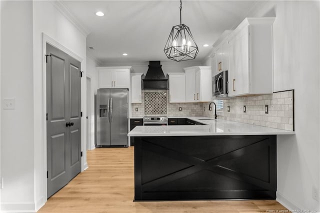 kitchen featuring white cabinetry, appliances with stainless steel finishes, pendant lighting, custom range hood, and light wood-type flooring