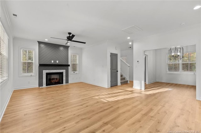 unfurnished living room featuring crown molding, ceiling fan with notable chandelier, light hardwood / wood-style floors, and a fireplace