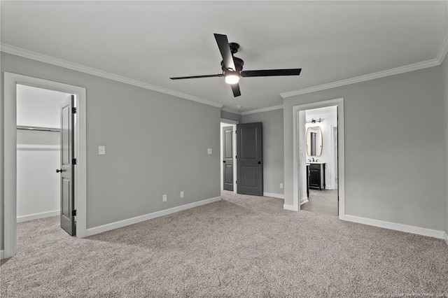 unfurnished bedroom with a spacious closet, light carpet, ceiling fan, and crown molding