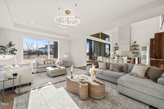 living room with an inviting chandelier, hardwood / wood-style floors, and a tray ceiling