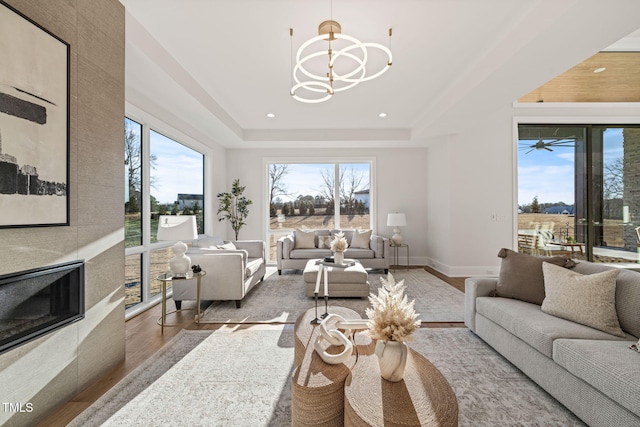 living room featuring a chandelier, a raised ceiling, and light hardwood / wood-style flooring