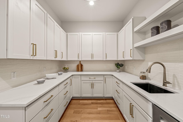 kitchen with white cabinetry, sink, and light stone countertops