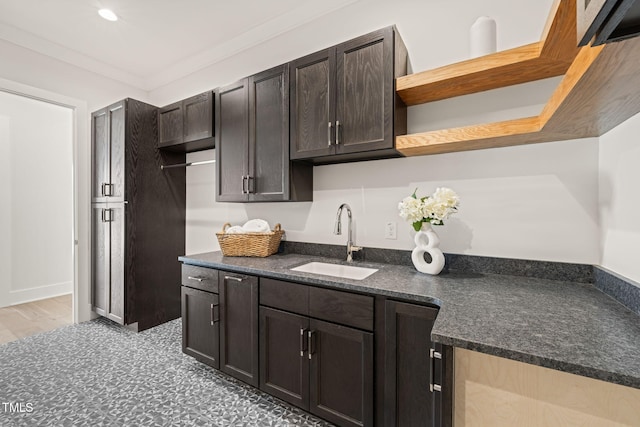 kitchen featuring dark brown cabinetry, sink, and crown molding