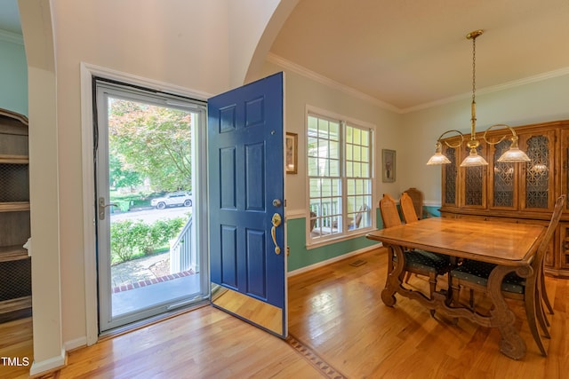 entryway with light wood finished floors, healthy amount of natural light, arched walkways, ornamental molding, and baseboards