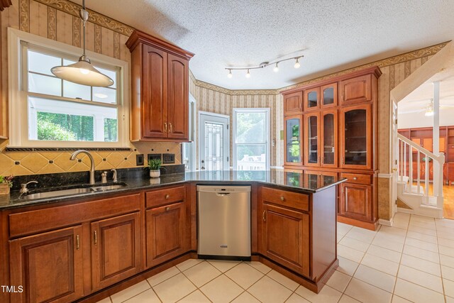 kitchen featuring wallpapered walls, dishwasher, a sink, a peninsula, and brown cabinetry