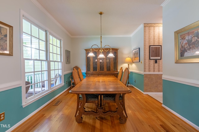 dining area featuring light wood-style floors, baseboards, ornamental molding, and a chandelier