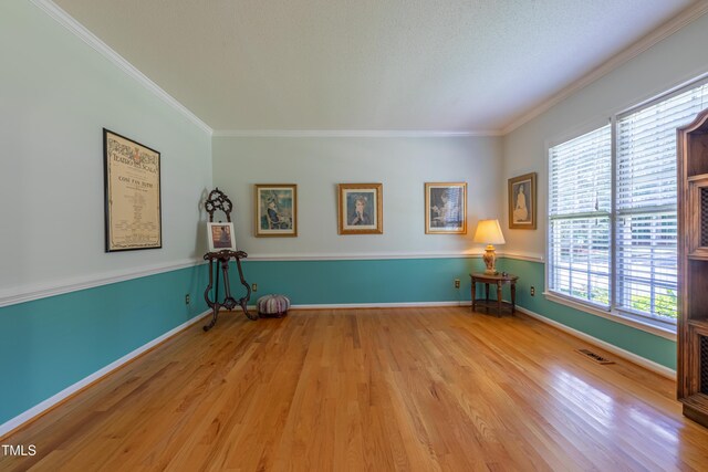 unfurnished room with wood finished floors, ornamental molding, and baseboards