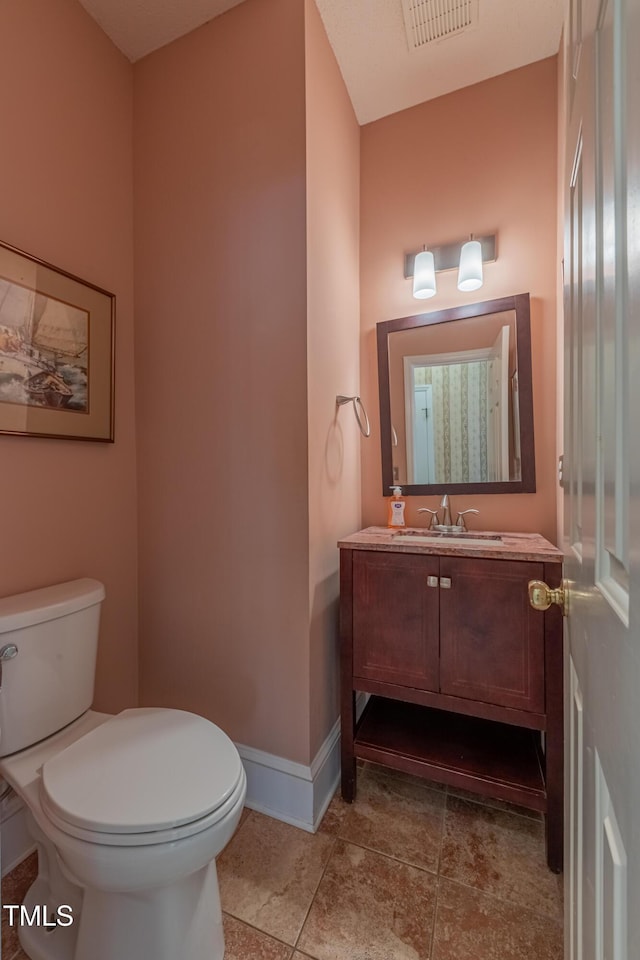 bathroom with toilet, vanity, baseboards, and tile patterned flooring