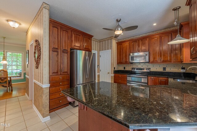 kitchen featuring appliances with stainless steel finishes, a sink, light tile patterned flooring, ceiling fan, and dark stone countertops