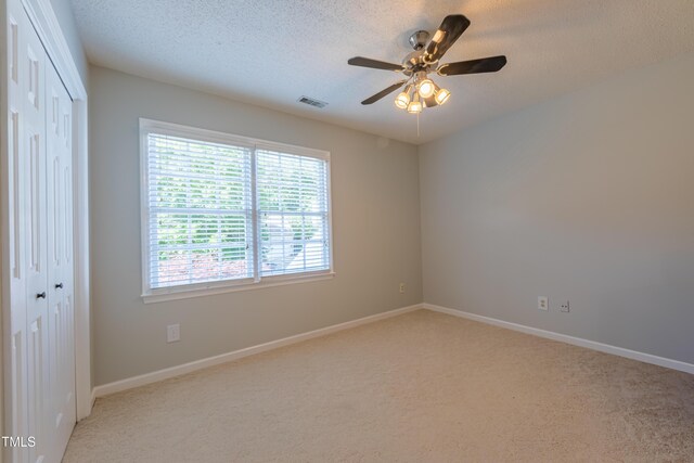 carpeted spare room with ceiling fan, a textured ceiling, and baseboards