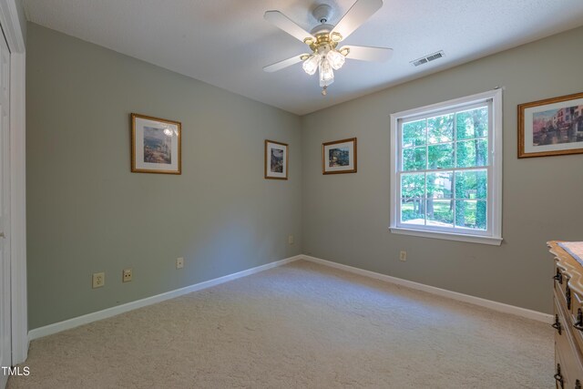 spare room with light colored carpet, ceiling fan, and baseboards