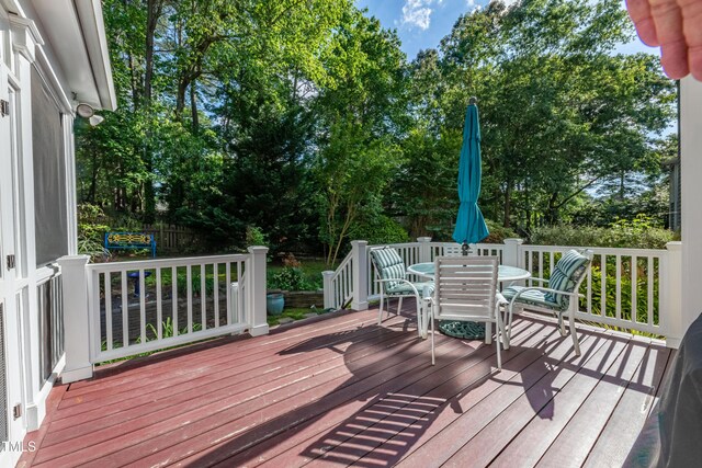 deck featuring outdoor dining area and view of scattered trees