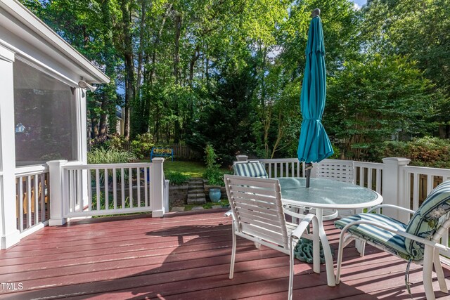 wooden deck featuring outdoor dining area and view of scattered trees