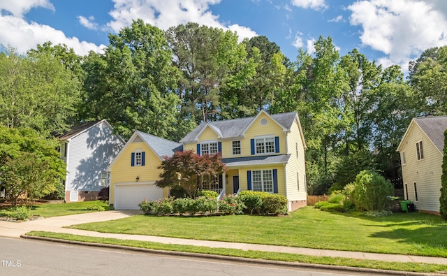 traditional home with driveway, a garage, and a front yard