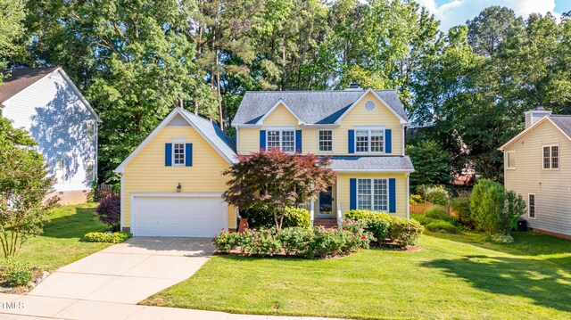 traditional-style home featuring concrete driveway, a front yard, and a garage