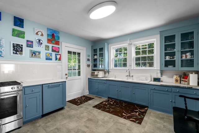 kitchen featuring stainless steel gas range, blue cabinetry, tasteful backsplash, and light tile flooring