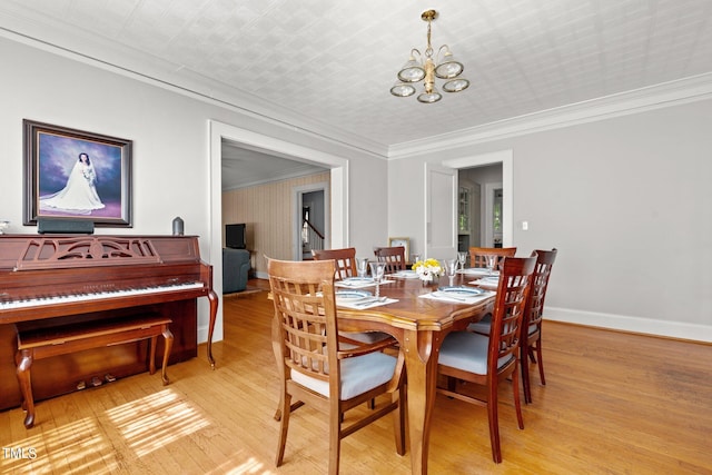 dining space featuring an inviting chandelier, ornamental molding, and light wood-type flooring