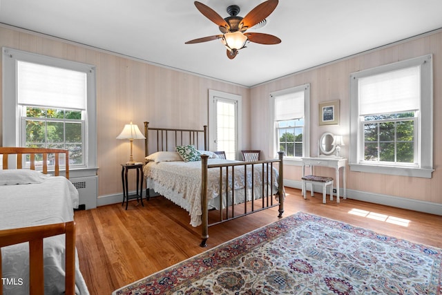 bedroom with wood-type flooring, ceiling fan, and radiator