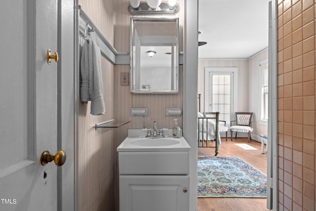 bathroom featuring wood-type flooring, ornamental molding, and large vanity