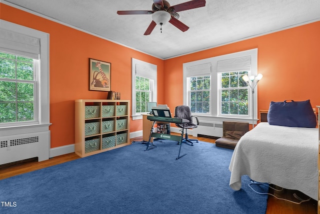 bedroom with ceiling fan, hardwood / wood-style flooring, ornamental molding, and radiator