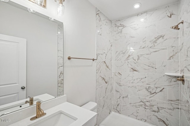 bathroom with tiled shower, vanity, and toilet