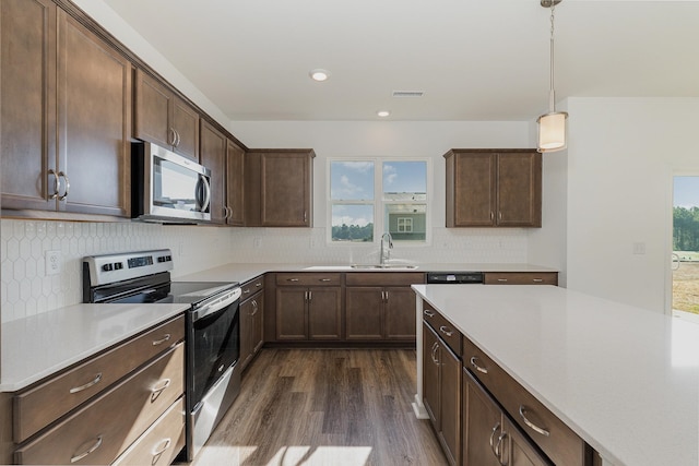 kitchen featuring decorative light fixtures, appliances with stainless steel finishes, dark hardwood / wood-style flooring, and a wealth of natural light