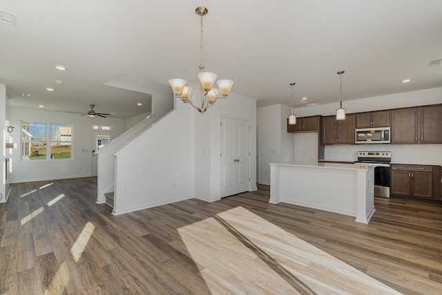 kitchen with ceiling fan with notable chandelier, appliances with stainless steel finishes, dark wood-type flooring, and tasteful backsplash