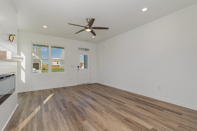 unfurnished living room with ceiling fan, a fireplace, and wood-type flooring