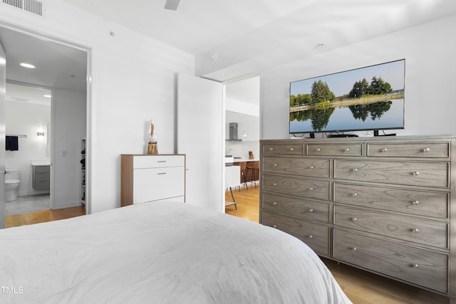 bedroom with light hardwood / wood-style floors and ensuite bath