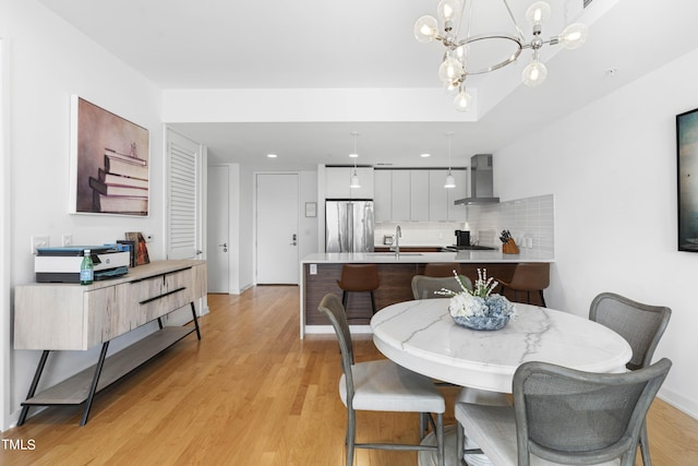 dining room with sink, a notable chandelier, and light wood-type flooring