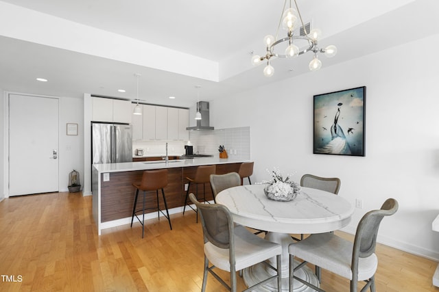 dining space featuring light hardwood / wood-style floors, a notable chandelier, and sink