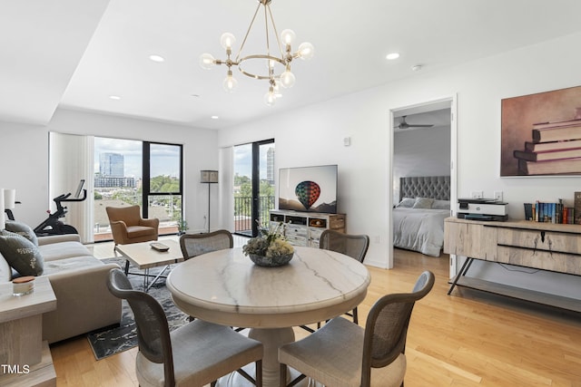 dining area featuring ceiling fan with notable chandelier and light wood-type flooring