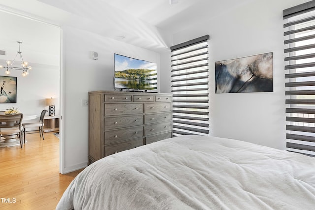 bedroom featuring a notable chandelier, light hardwood / wood-style floors, and multiple windows