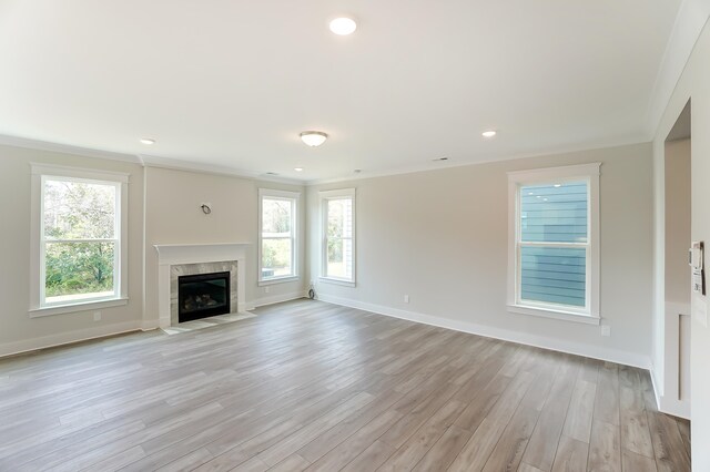 2023 Seneca Dr Lot 32, Raleigh, NC 27604 - unfurnished living room with a tiled fireplace, a healthy amount of sunlight, and light wood-type flooring