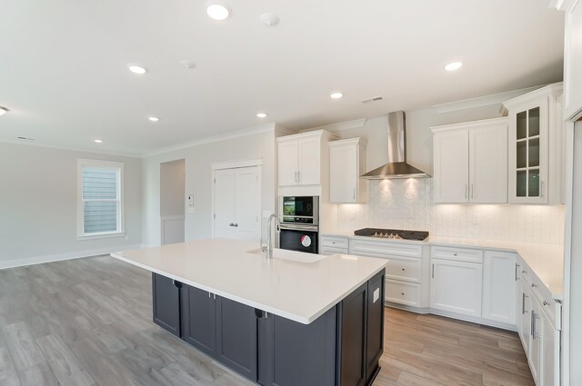 2023 Seneca Dr Lot 32, Raleigh, NC 27604 - kitchen featuring light hardwood / wood-style floors, white cabinets, a kitchen island with sink, wall chimney exhaust hood, and backsplash
