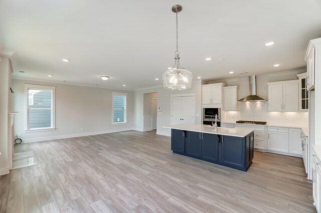 2023 Seneca Dr Lot 32, Raleigh, NC 27604 - kitchen featuring wall chimney exhaust hood, light hardwood / wood-style floors, white cabinets, and a center island with sink
