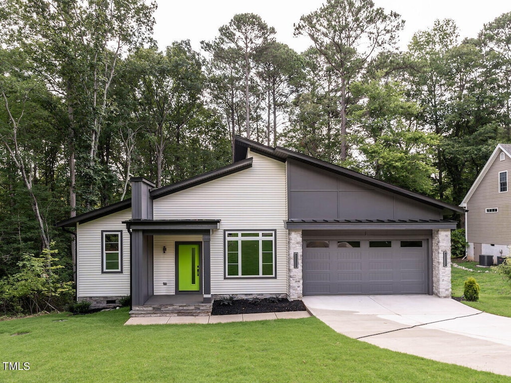 view of front facade with central air condition unit, a front yard, and a garage