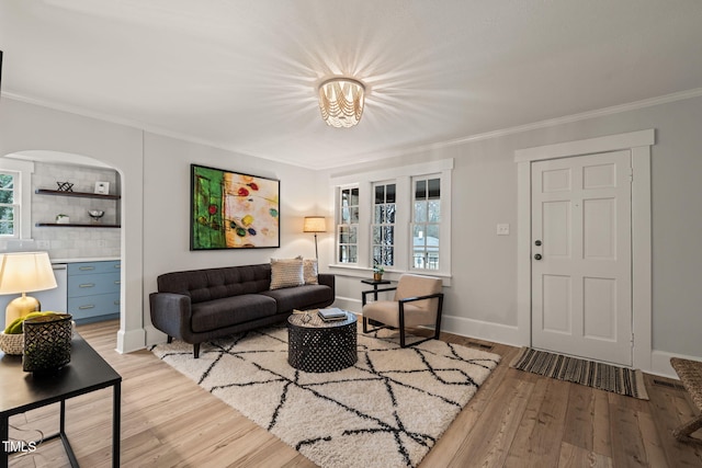 living room with plenty of natural light, ornamental molding, and light hardwood / wood-style flooring