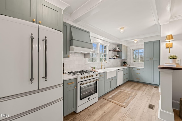 kitchen with sink, premium range hood, backsplash, white appliances, and light wood-type flooring