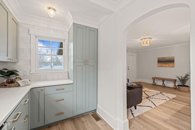 kitchen featuring backsplash, crown molding, and light hardwood / wood-style flooring