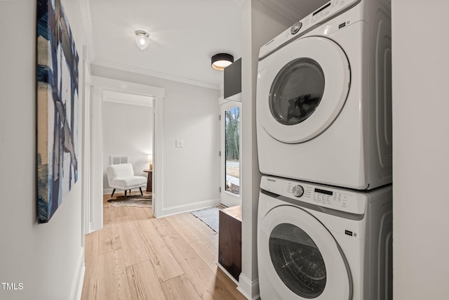 washroom featuring light hardwood / wood-style floors, ornamental molding, and stacked washer / dryer