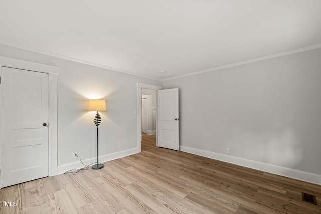 spare room featuring crown molding and light hardwood / wood-style flooring