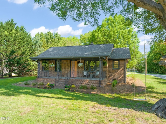 view of front of home with a front lawn, covered porch, brick siding, and roof with shingles