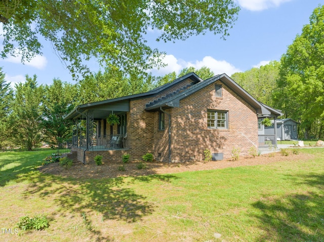 view of side of home featuring a storage shed, a yard, an outdoor structure, a porch, and brick siding