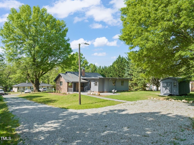 view of front of house featuring gravel driveway, an outbuilding, a storage shed, and a front yard