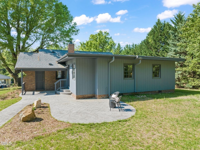 rear view of property featuring a lawn, a chimney, and a patio