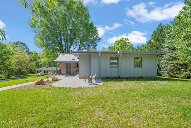 rear view of house featuring a patio area, a chimney, a yard, and crawl space