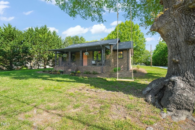 exterior space featuring a porch, brick siding, and a yard
